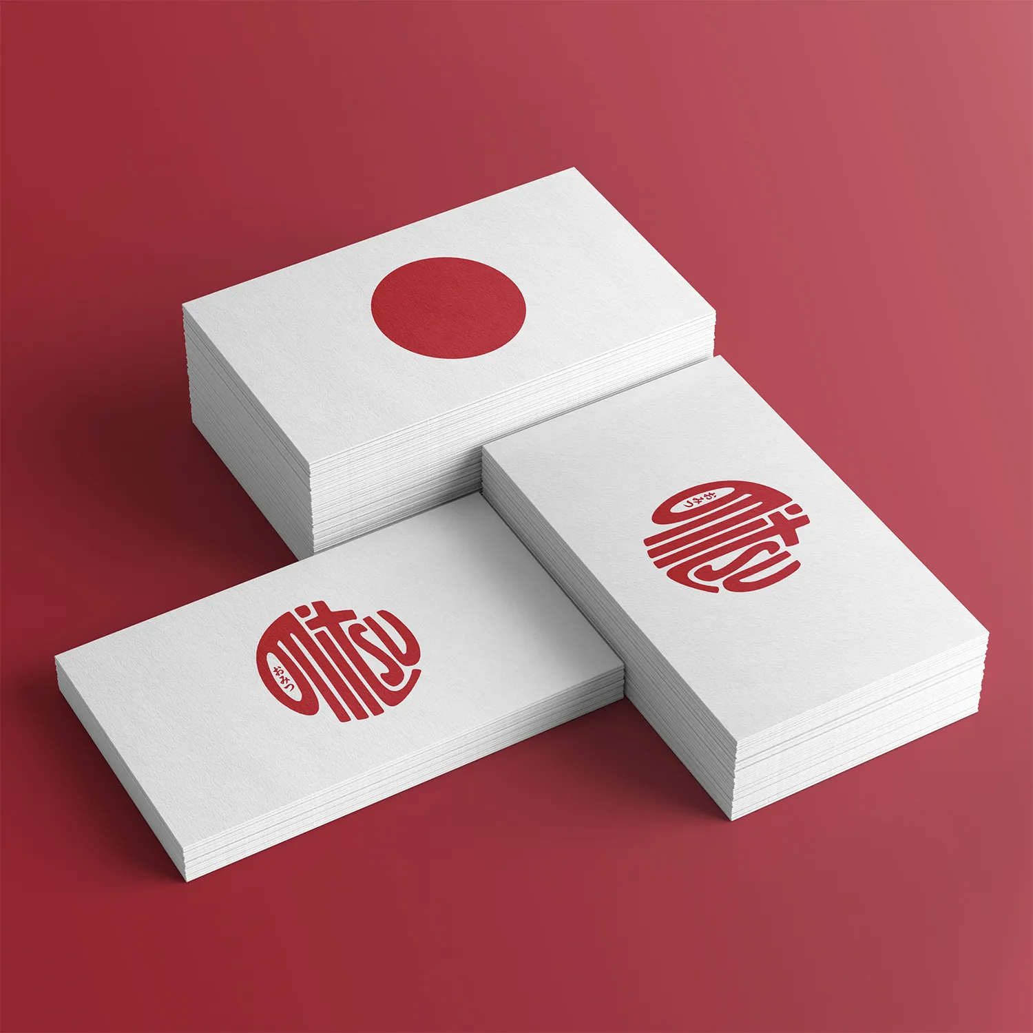 White business cards displaying the red circular Omitsu logo on a deep red background